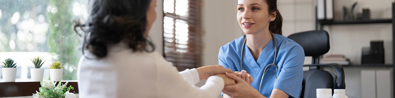 Pflegekraft hält Hände einer Patientin.